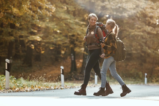 Shot van een tienermeisje en haar moeder die praten tijdens een wandeling samen door het bos in de herfst.