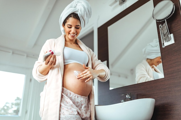 Shot van een vrouw die crème aanbrengt op haar zwangere bel