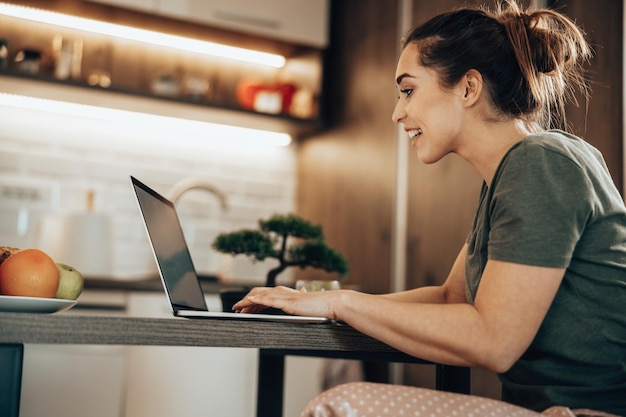 Shot van een vrouw die 's ochtends thuis op het net surft op een laptop.