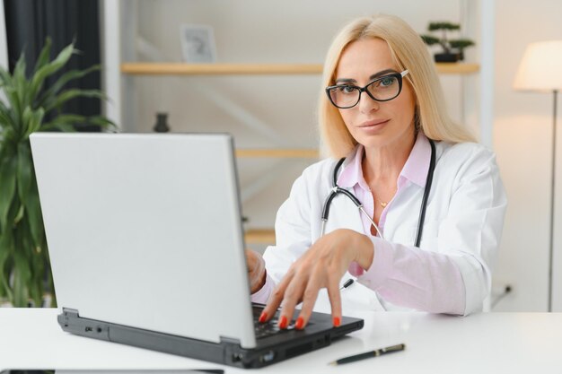 Shot van een vrouwelijke arts die aan het werk zit aan een bureau voor een laptop