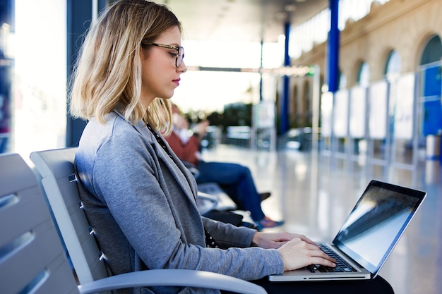 Shot van mooie jonge zakenvrouw met behulp van haar laptop in het treinstation.