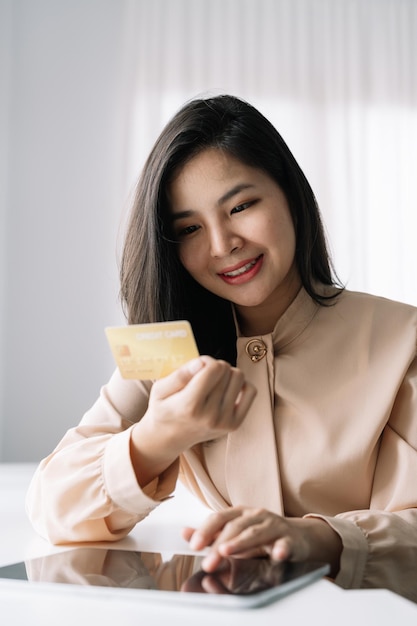 Shot of woman hold bank credit card and type on laptop shopping online using digital tablet for buying goods or ordering online entering bank accounts and details in online banking offer