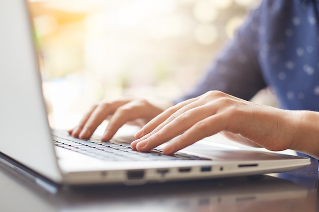 A shot of woman`s hands typing on keyboard while chatting with friends using computer laptop