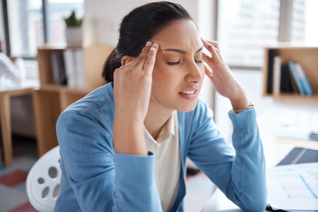 Shot of a young businesswoman looking stressed while working at her desk in a modern office