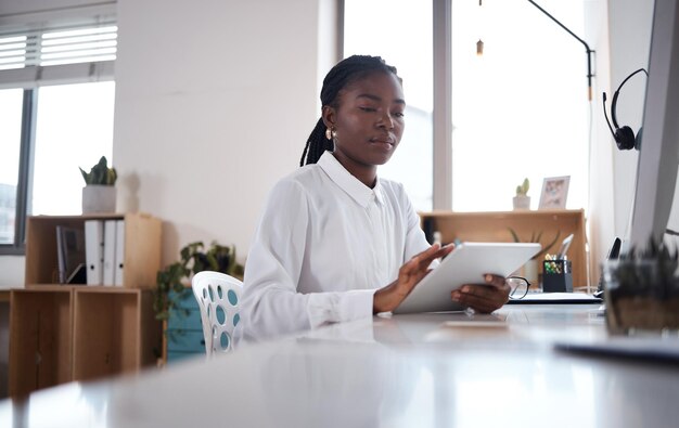 Shot of a young businesswoman using a digital tablet at her desk in a modern office