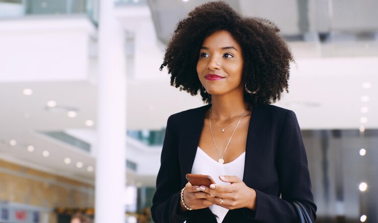 Photo shot of a young businesswoman using a smartphone while walking through a modern office
