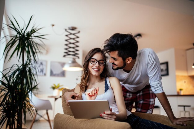 Shot of a young couple embracing while using tablet at home