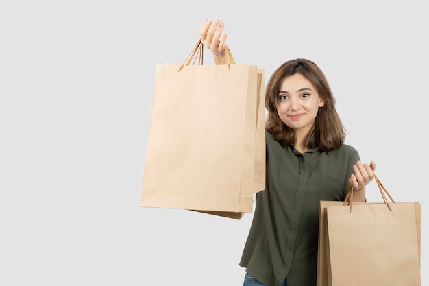 Shot of young female model with craft bags standing over white. High quality photo