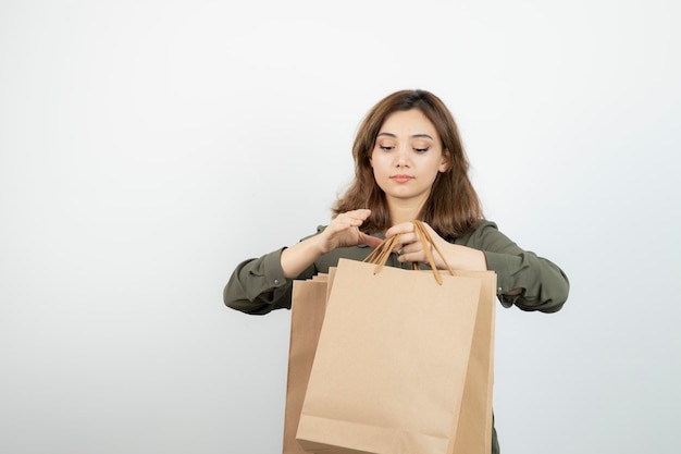 Shot of young female model with craft bags standing over white. High quality photo