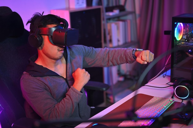 shot of young man playing boxing game in virtual reality glasses entertainment and technology concept