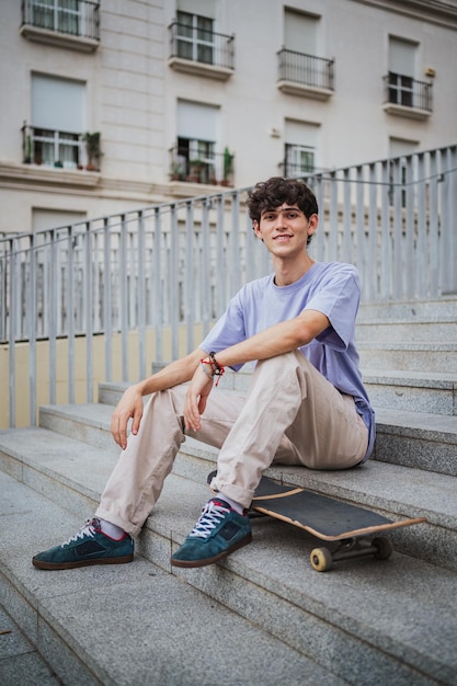 Shot of young man who practices skateboarding He is sitting on concrete stairs