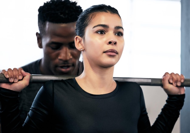 Shot of a young man and woman working out with a barbell in a gym