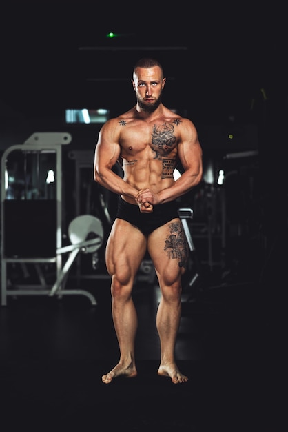 Shot of a young muscular bodybuilder showing his perfect muscles while posing after working out at the gym. Looking at camera.