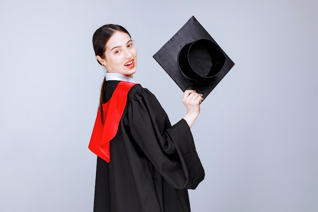 Shot of young student in gown showing her graduation cap. High quality photo