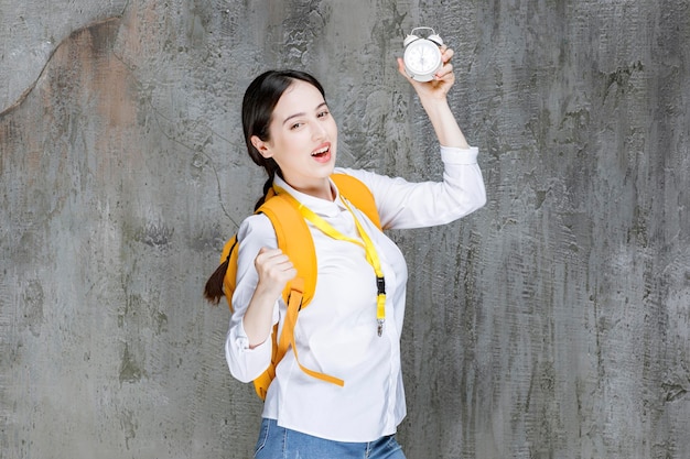 Shot of young student with backpack showing time on clock. High quality photo