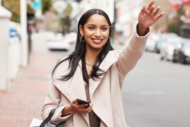 Shot of a young woman hailing a cab after shopping