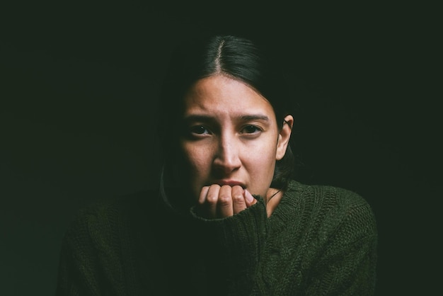 Shot of a young woman looking nervous against a dark background