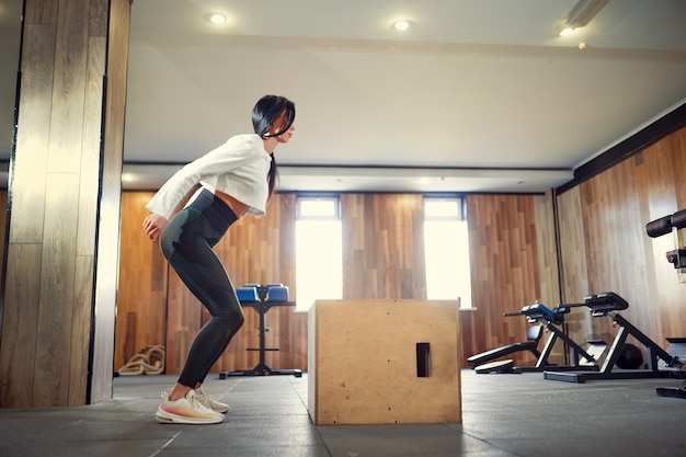 Colpo di giovane donna che lavora con una scatola in palestra. scatola dell'atleta femminile che salta ad una palestra di addestramento funzionale