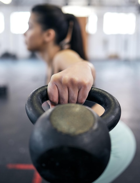 Shot of a young woman working out with kettle bell weights in a gym