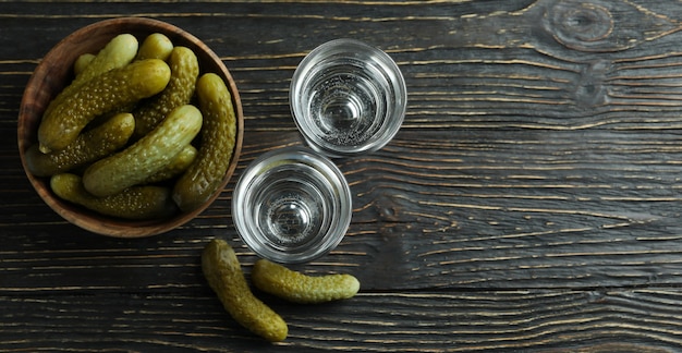Shots of drink and pickles on wooden wall