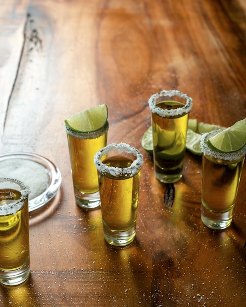 Foto scatti di tequila con sale e limone su un tavolo di legno festive cinco de mayo sullo sfondo