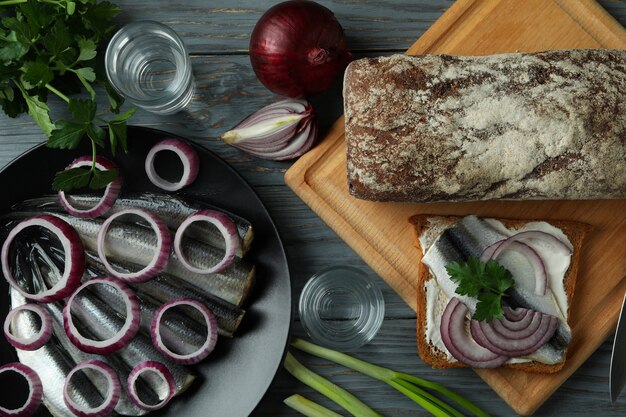 Shots of vodka and tasty snacks on wooden table, top view