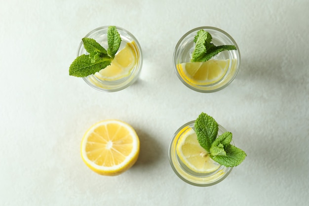 Снимки с долькой лимона и мятой на белом текстурированном столе