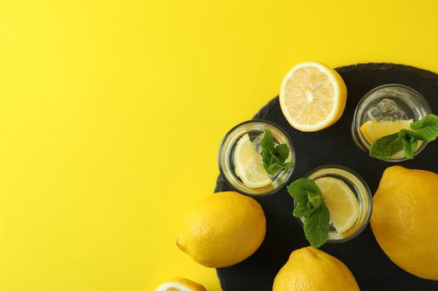 Colpi con fetta di limone e menta sul vassoio sulla superficie gialla