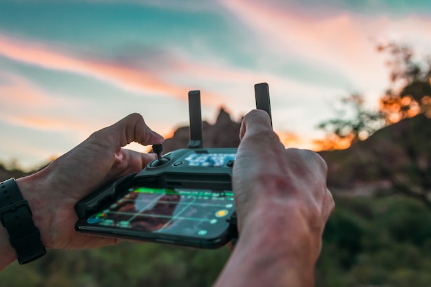 Photo shoulder hand piloting drone at sunset