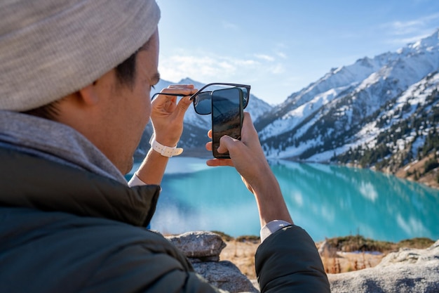 山の湖の写真を撮る男の肩越しの画像