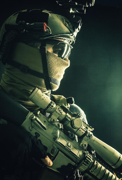 Shoulder portrait of army elite troops sniper antiterrorist tactical team marksman wearing helmet with thermal imager hiding face behind mask armed rifle with optical scope studio shoot on black