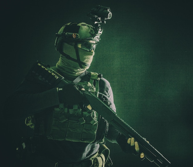 Photo shoulder portrait of army elite troops soldier antiterrorist tactical team wit shotgun helmet with thermal imager hiding face behind mask armed rifle with optical scope studio shoot on black