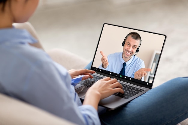 Photo over shoulder shot of woman using laptop video chat