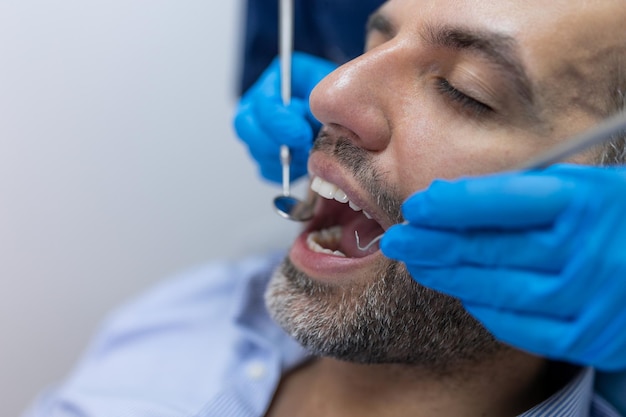 Over the shoulder view of a dentist examining a patients teeth in dental clinic Man having his teeth examined by a young female dentist