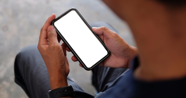 Over shoulder view man hands holding smart phone with white screen Close up