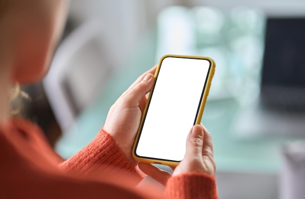 Over shoulder view of woman holding smartphone white mock up\
screen