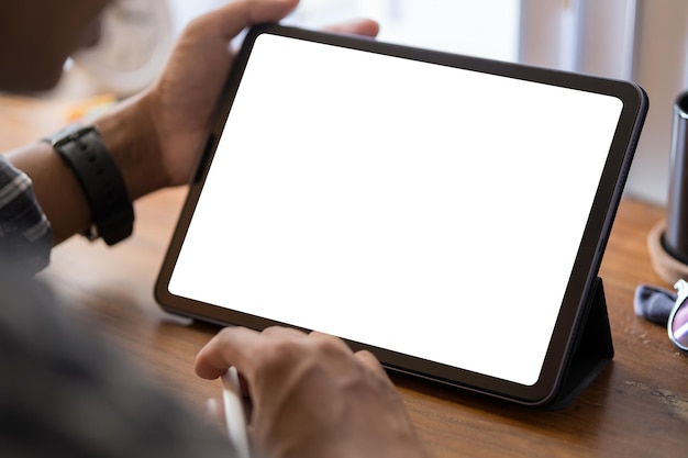 Over shoulder view of young man using digital tablet on white table at home office