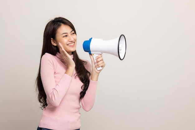 확성기로 큰 소리로 외쳐 젊은 아름다운 아시아 여성이 할인된 가격으로 제품에 대한 판촉 및 광고에 대해 음성으로 발표합니다. 쇼핑 및 패션 개념