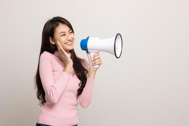 Shout out loud with megaphone Young beautiful asian woman woman announces with a voice about promotions and advertisements for products at a discounted price Shopping and fashion concept