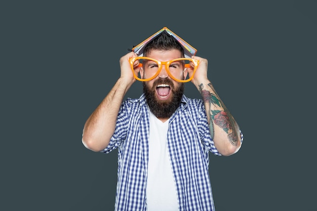 Shouting funny bearded man in party glasses with book on head