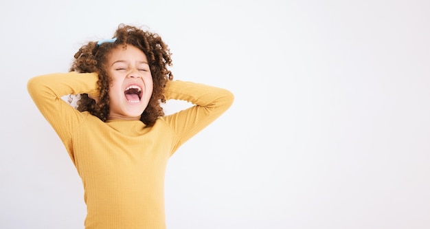 Shouting loud and mockup with a girl child in studio on a white background covering her ears Children sound and audio with a young kid screaming or yelling on empty space for ADHD or autism