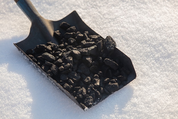 Shovel full of coal in the snow in winter