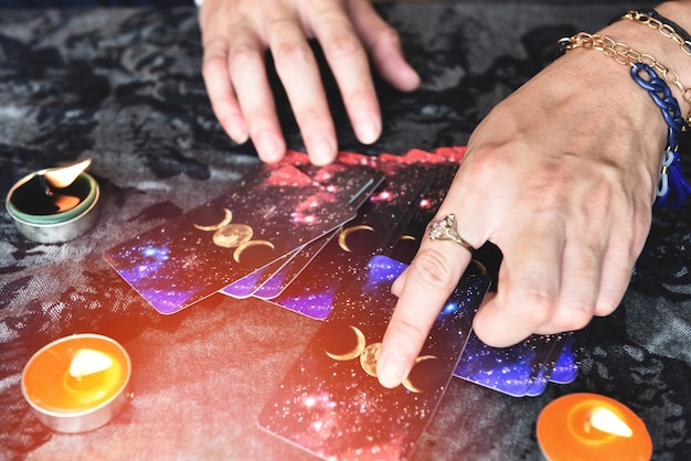 Photo show fortune tellers of hands holding tarot cards and tarot reader with candle light on the table, performing readings magical performances, things mystical astrologists forecasting concept