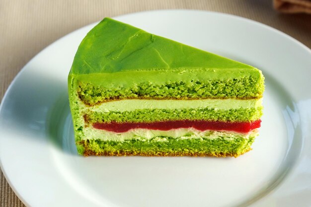 Foto mostrando un delizioso pezzo di torta verde su un piatto bianco incontaminato che tenta lo spettatore