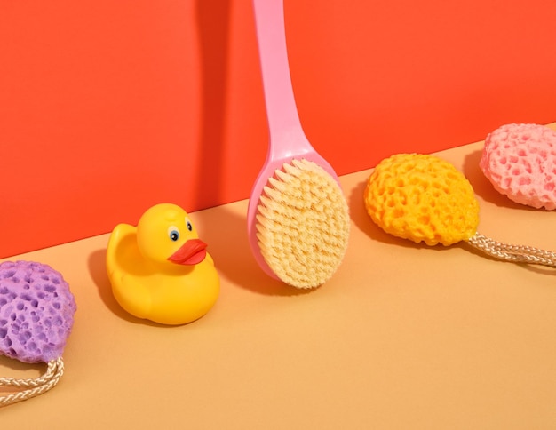 A shower brush yellow rubber duck and sponges of different colors and shapes skin routine in bathroom