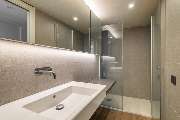 Photo shower cabin and wash basin in renovated bathroom with mirror