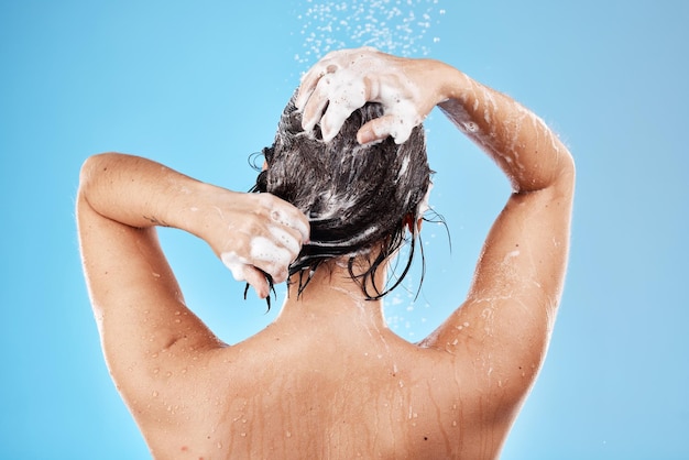 Shower hair and shampoo with a woman cleaning in studio on a blue background for haircare or hygiene Water wellness and luxury with a female washing her body in the bathroom for care or treatment