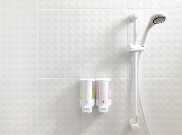 壁にシャワーとシャンプーのボトルが付いた浴室のシャワーヘッド