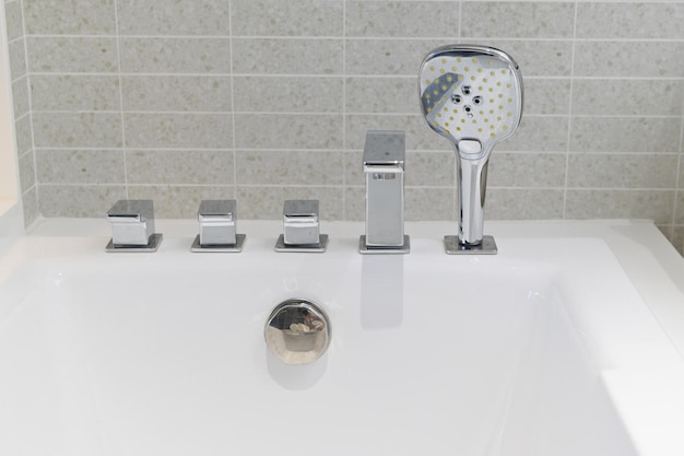 Shower head and faucet bathtube in white bathroom