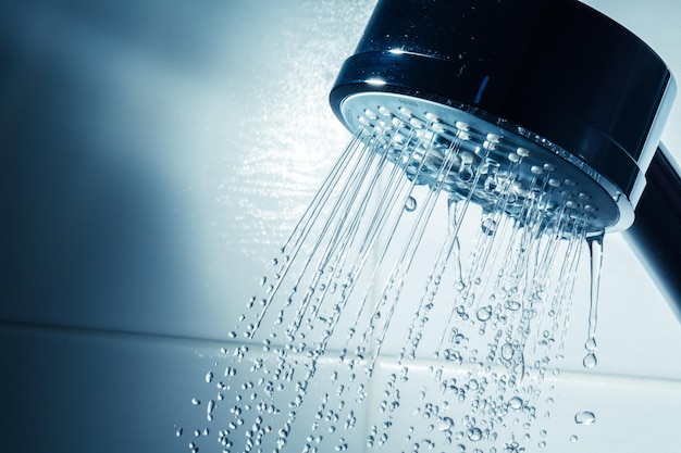 Shower Head with Water Stream on Blue Background